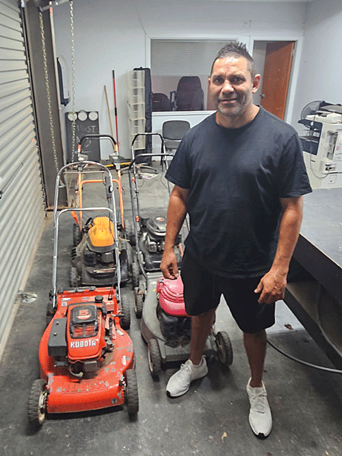 A student standing inside a shed beside lawnmowers during CCNI’s Introduction to Small Engines workshop at Moree Campus, where learners developed practical maintenance and workshop skills in a hands-on community learning environment.