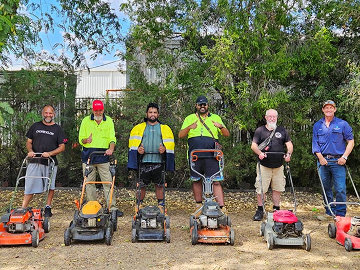 Six students stand outdoors beside lawnmowers during CCNI’s Introduction to Small Engines workshop at Moree Campus, where learners developed practical maintenance and workshop skills in a hands-on community learning environment.